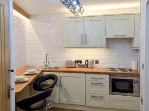 a kitchen with white cabinets and a black chair at Chunal Apartment - Uk12958 in Glossop