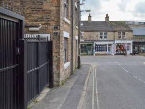 an empty street next to a brick building with a gate at Chunal Apartment - Uk12958 in Glossop