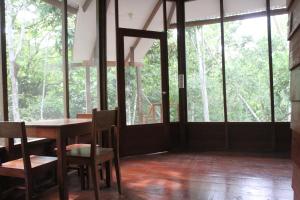 a dining room with a table and chairs and windows at La Musa Verde in Tarapoto