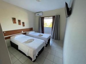 a hotel room with two beds and a television at Pousada Costa dos Corais in São José da Coroa Grande