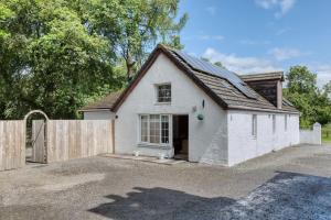 a small white house with a wooden fence at Hayloft at Bonnyside House in Bonnybridge