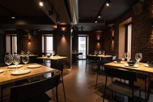 a restaurant with wooden tables and chairs with wine glasses at Hotel Atari in Donostia-San Sebastián