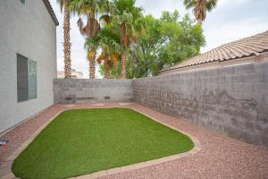 un patio con una pared de retención y césped verde en Splendid House With Pool! en Las Vegas