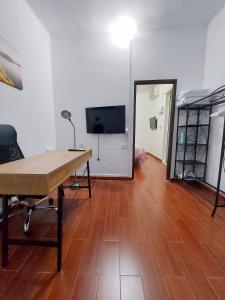 Pokój z biurkiem, telewizorem i drewnianą podłogą. w obiekcie Casa Rebeca w mieście Teror