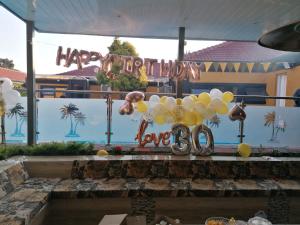 een hoop ballonnen en een bord met gefeliciteerd jubileum bij National Lodge in Benoni
