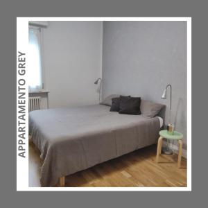 1 dormitorio con 1 cama y 1 mesa con lámpara en GREY IL NUOVO BICAMERE CON TERRAZZA E PARCHEGGIO, en Trento