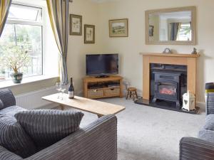 een woonkamer met een bank en een open haard bij Grassgarth Cottage in Redmire