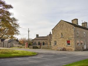 un antiguo edificio de piedra con un banco delante de él en Grassgarth Cottage, en Redmire