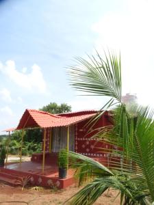 a small red house with a palm tree in front of it at MangoHut Farmhouse Pool Villa in Hyderabad