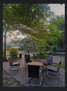 a group of chairs and a table and a tree at Lotus 2 Guest House in Borobudur