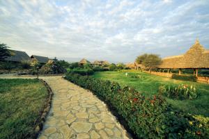 a stone path through a garden with flowers and houses at AA Lodge Amboseli in Amboseli