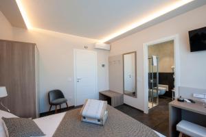 a room with a bed and a chair and a mirror at Brichett Deluxe Rooms in Alba