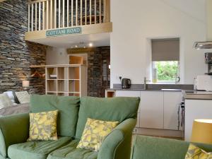 a living room with a green couch and a kitchen at Cottam Road in Threlkeld