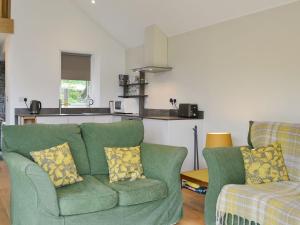 a living room with a green couch and a kitchen at Cottam Road in Threlkeld