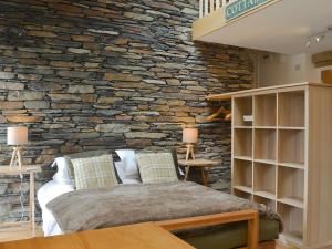 a bedroom with a stone wall with a bed at Cottam Road in Threlkeld