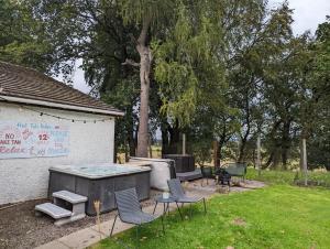 a backyard with a table and chairs and a tree at Doocot At Bonnyside House in Bonnybridge