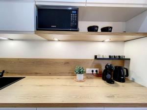 a kitchen with a wooden counter top with a microwave at AppartChic - appartement standing - plein Centre & Parking privé in Créon