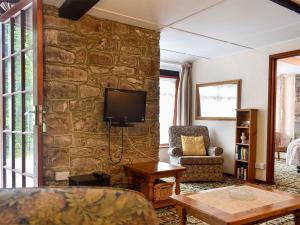 a living room with a stone wall with a tv at Lower Chinkwell-uk12426 in Widecombe in the Moor