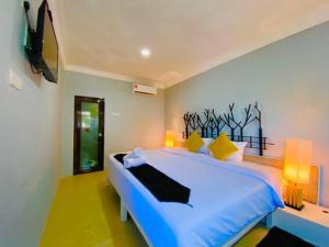 a bedroom with a large bed with blue sheets and yellow pillows at FAT MERMAID GUESTHOUSE in Pantai Cenang