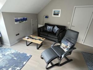 a living room with a leather chair and a couch at River Vista Retreat - Luxury duplex Apt - Views - Parking - Cycle storage - Spa access option in Backbarrow