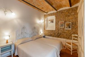 1 dormitorio con cama y pared de piedra en Podere San Giuseppe Montalcino, en Montalcino