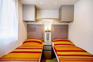twee bedden in een kleine kamer met gele en rode strepen bij Camping Grande Italia Belvedere in Chioggia