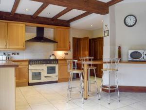 a kitchen with wooden cabinets and a counter with bar stools at Springfields in Leek