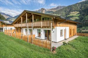 a large wooden house with a fence in a field at Lagar Apartement Pircher Schnallele in San Leonardo in Passiria
