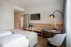 オーバーハウゼンにあるHotel Oberhausen Neue Mitte affiliated by Meliáのベッドとテーブルと机があるホテルの部屋