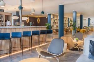 ein Restaurant mit blauen Stühlen und einer Bar in der Unterkunft Hotel Oberhausen Neue Mitte affiliated by Meliá in Oberhausen