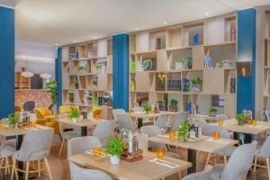 a restaurant with tables and chairs and shelves with plants at Hotel Oberhausen Neue Mitte affiliated by Meliá in Oberhausen