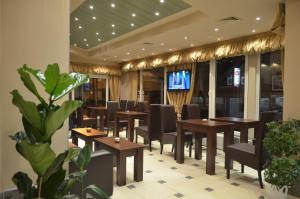 a restaurant with wooden tables and chairs and a tv at Garni Hotel Lion in Jagodina