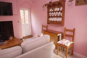 a living room with pink walls and a white couch at The Gardener's Cottage in Leominster