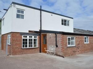 una casa de ladrillo con una silla delante en Moss Hall Barn en Eaton