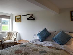 Un dormitorio con una cama con almohadas azules. en Moss Hall Barn en Eaton