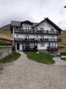 un gran edificio blanco al lado de una colina en Cabana Transalpina en Ranca