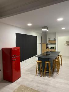 a kitchen with a red refrigerator and a table with stools at Apartamento Concarera in Tudela