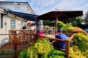 two men sitting at a table under an umbrella at The Jug And Bottle in Heswall