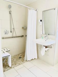 a bathroom with a sink and a shower with a mirror at Soleado Hotel in Fort Lauderdale