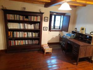 Zimmer mit einem Schreibtisch und Bücherregalen mit Büchern in der Unterkunft Albergue Rectoral de Romean in Lugo