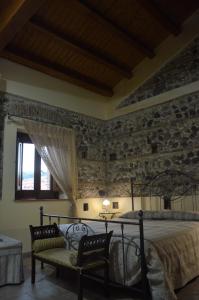 a bedroom with a bed and a stone wall at Valle degli Agrumi in San Pier Niceto