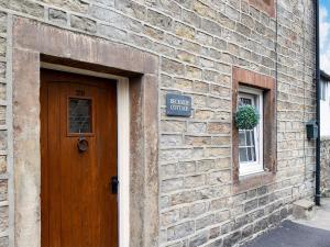 a brick building with a door and a sign on it at Beckside Cottage in Silsden
