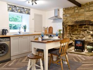a kitchen with a table and chairs and a fireplace at Beckside Cottage in Silsden