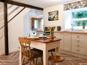 a kitchen with a wooden table and chairs and a sink at Beckside Cottage in Silsden