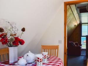 a table with a checkered table cloth and a vase with flowers on at Poppy Lodge in Kingsdown
