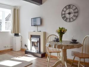 a living room with a table and a clock on the wall at Weavers Houses in Hayfield