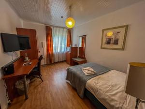 a hotel room with a bed and a desk and a television at Hotel Restaurant Hüftgold in Plettenberg