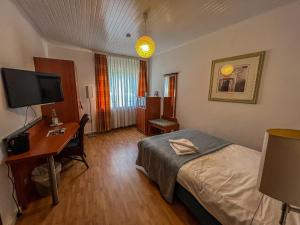a hotel room with a bed and a desk and a television at Cici Monteurunterkünfte Plettenberg Oestertal in Plettenberg