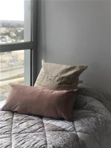uma almofada sentada em cima de uma cama ao lado de uma janela em Los Cardos Suites em Neuquén