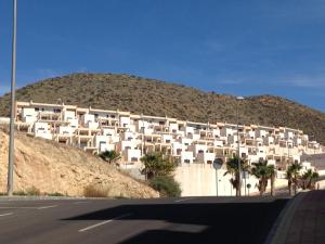 a building on the side of a hill with palm trees at Apartment Mojon Hills in Isla Plana